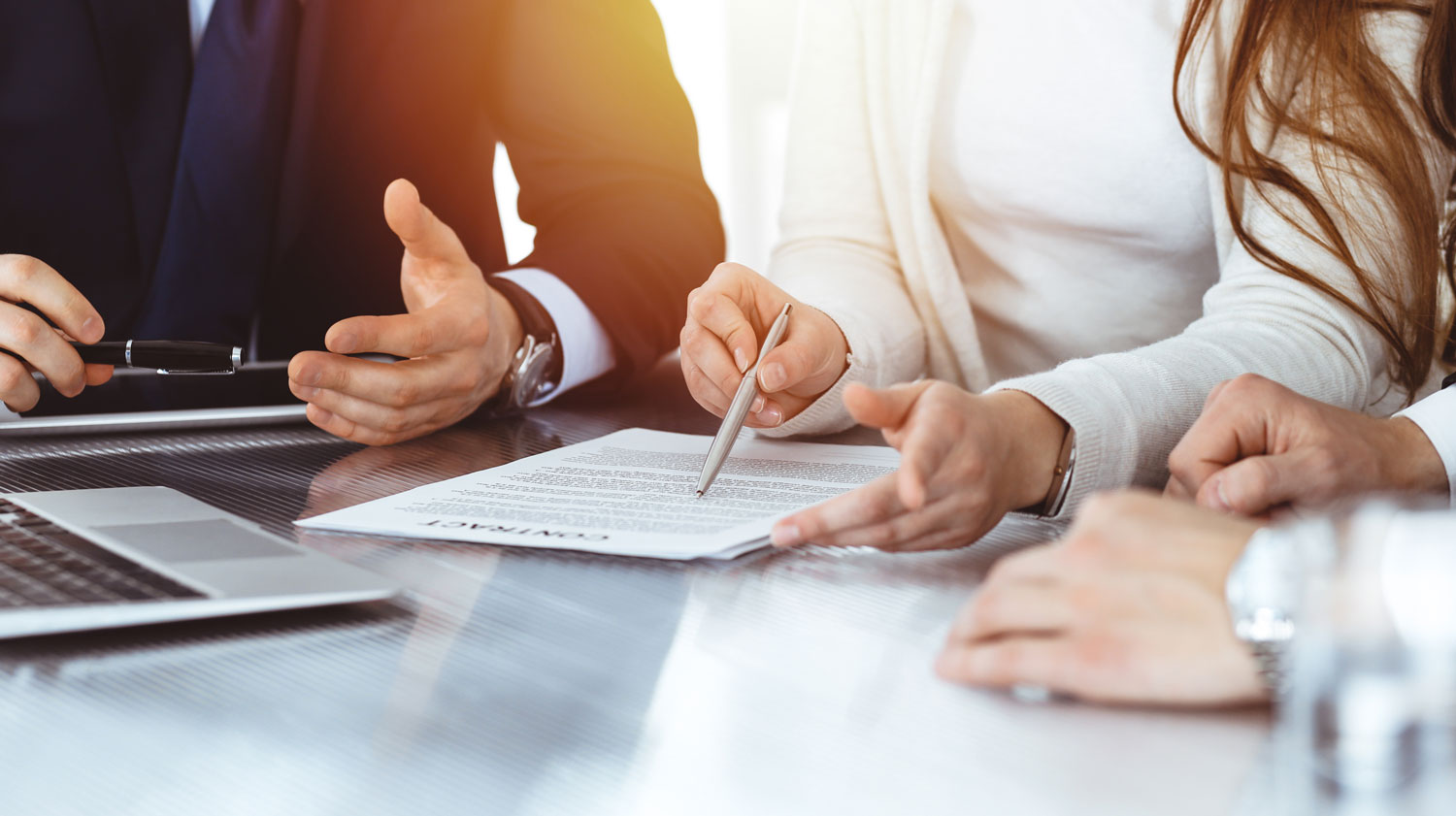 A close-up of business professionals gathered around a contract, reviewing and preparing to sign a legal document on a glossy conference table. The image shows a pen in hand, emphasizing the seriousness and precision of legal communication. This visual reflects Postalocity’s tailored business mail solutions for the legal industry—offering secure, HIPAA-compliant processing for legal-sized paper formats used in court filings, contracts, and regulatory notices. It conveys the importance of document accuracy, confidentiality, and reliable delivery for legal professionals.