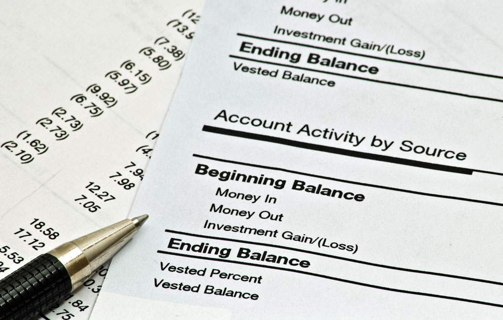 A close-up of a printed financial document showing detailed account activity, including beginning and ending balances, money in and out, and investment gains or losses. A pen rests beside the page, suggesting active review or preparation for mailing. This visual emphasizes the importance of accuracy and professionalism in billing cycles. It represents Postalocity’s automated statement and invoice mailing services—ideal for organizations handling recurring billing or municipal contracts with options for remittance stubs, envelope customization, and certified mail compliance.